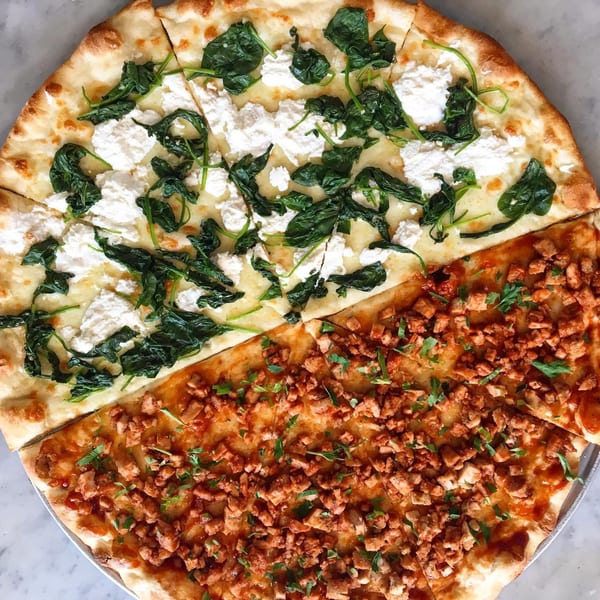 Half spinach and ricotta pizza, half chicken pizza, sliced and ready to eat.