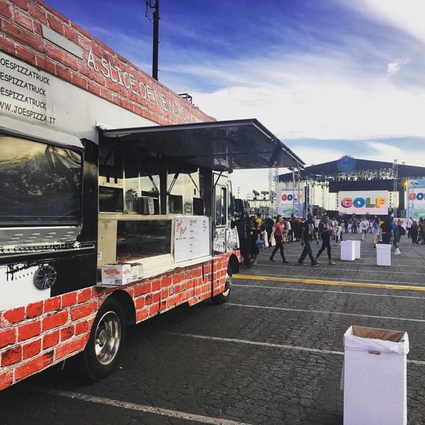 Joe's Pizza food truck with a brick design, serving customers at an outdoor event.