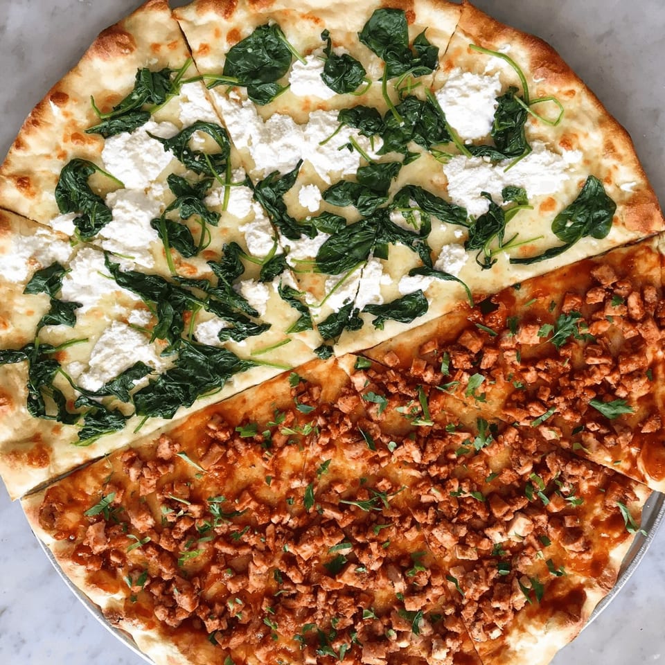 A Joe's pizza split in half, one side with spinach and ricotta, the other with diced chicken.