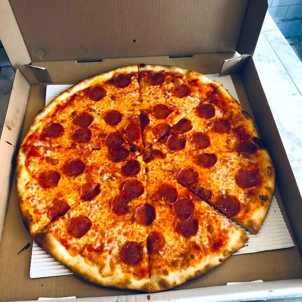 A Joe's Pizza pepperoni pizza with one slice removed, in a cardboard box.